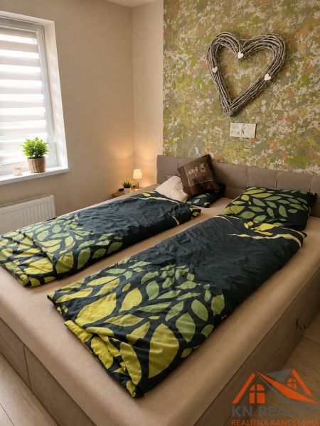 Schlafzimmer in einer 3-Zimmer-Wohnung mit einem Bett und einem dekorativen Herz an der Wand.