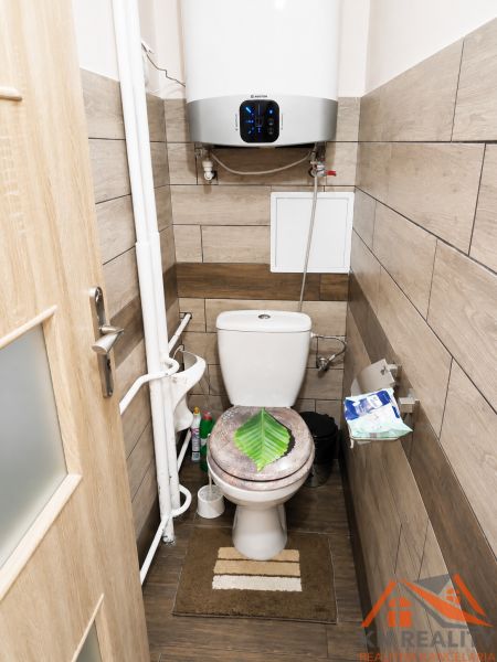 Badezimmer in einer 3-Zimmer-Wohnung mit Holzboden und einem hängenden Boiler.