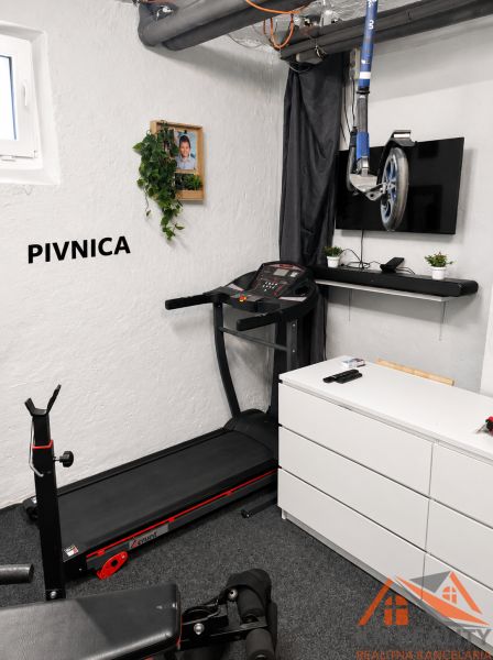 Fitness-Ecke mit Laufband, Fernseher und Hantelbank im Keller einer 3-Zimmer-Wohnung.