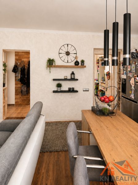 Innenraum einer 3-Zimmer-Wohnung mit Holzboden, bequemen Sitzgelegenheiten und Regalen.