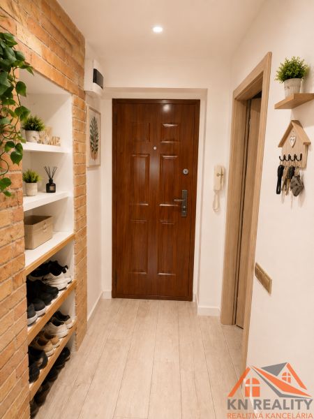 Eingang in eine 3-Zimmer-Wohnung mit Ziegelwand und Boden in Holzoptik.