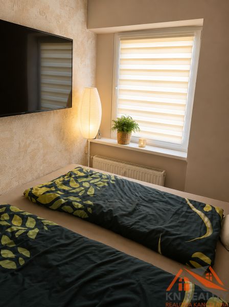 Ein abgegrenzter Bereich des Schlafzimmers in einer 3-Zimmer-Wohnung, ein großer Fernseher und eine Pflanze auf der Fensterbank.