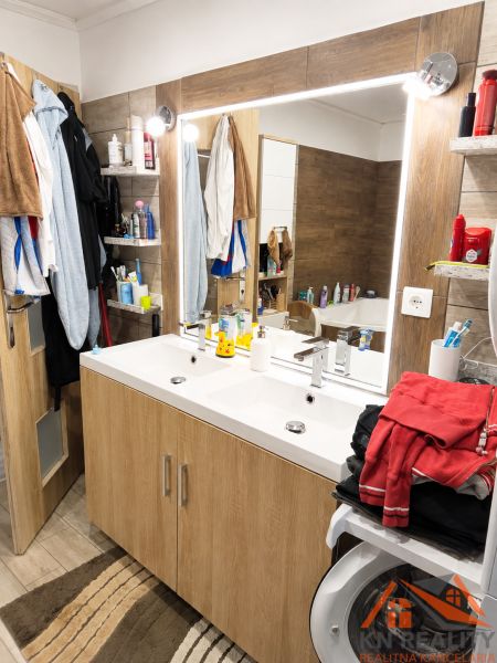 Badezimmer in einer 3-Zimmer-Wohnung mit Holzboden und Doppelwaschbecken.