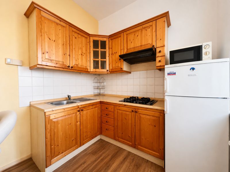 Küche in einer Einzimmerwohnung mit Holzschränken und einem Boden in Holzoptik.