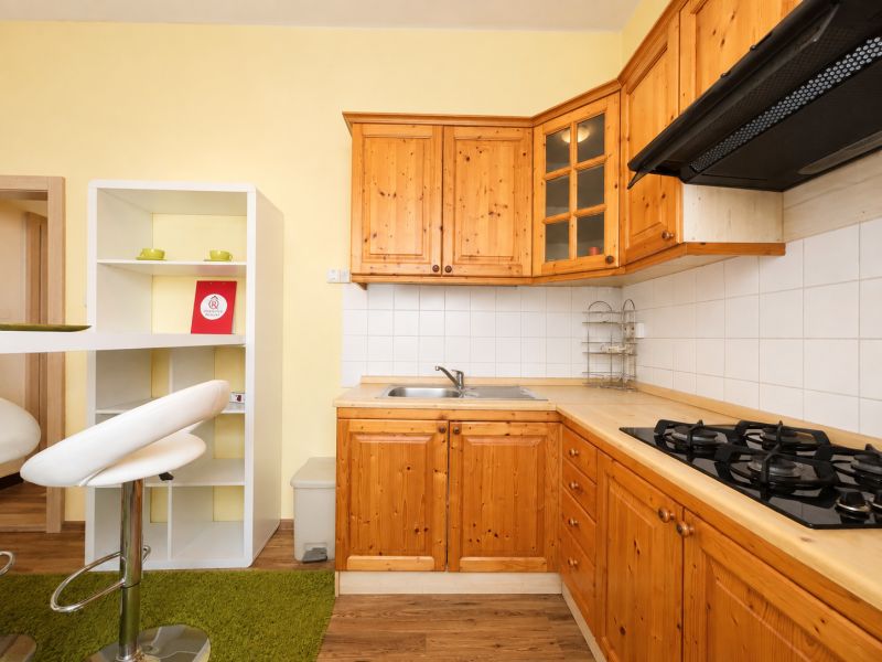 Küche in einer Einzimmerwohnung mit Holzschränken und Boden in Holzoptik.