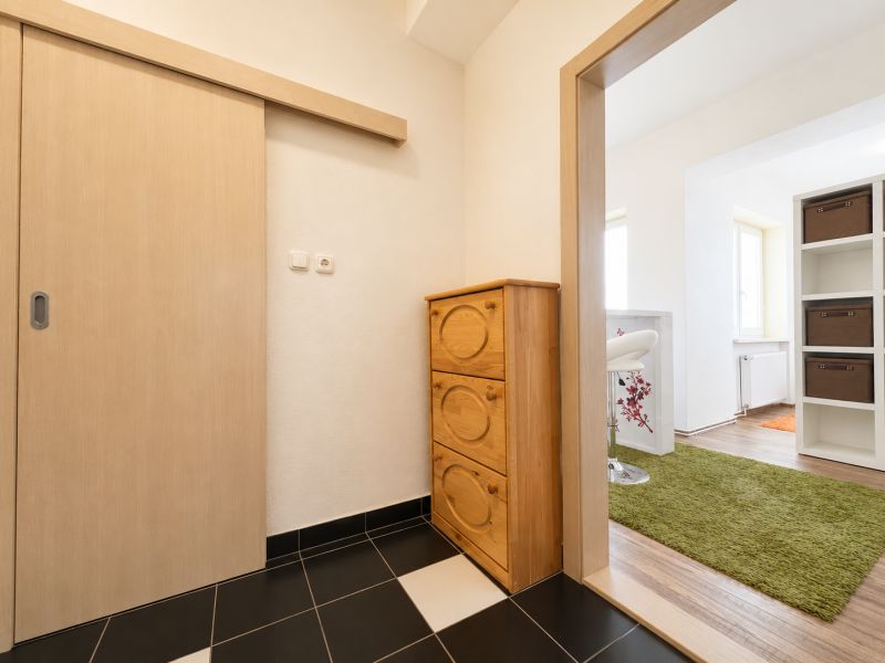 Diele mit einer Holzkommode, einem Boden mit Holzdekor und einem grünen Teppich.