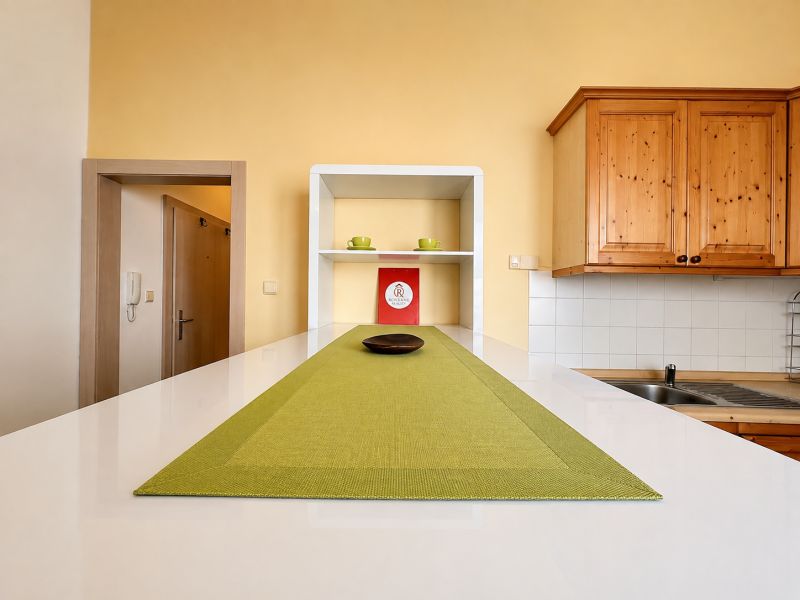 Küchenzeile mit Holzschränken und grüner Tischdecke in einer Einzimmerwohnung.