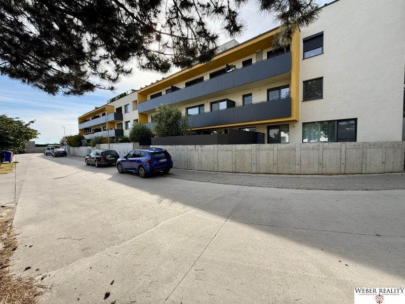 Mehrfamilienhaus in der Broskyňová-Straße in Rovinka mit einem Parkplatz davor.