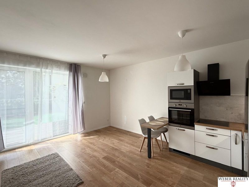 Küche in einer 2-Zimmer-Wohnung mit Holzboden und eingebauten Geräten.