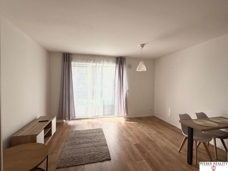 Wohnzimmer mit Esstisch und Holzboden in einer Zweizimmerwohnung.