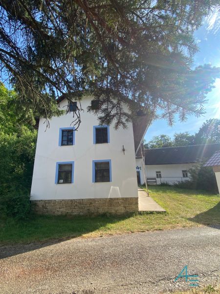 Ein Einfamilienhaus in Brestovec in Brestovec unter Bäumen mit weißer Fassade und blauen Fenstern.