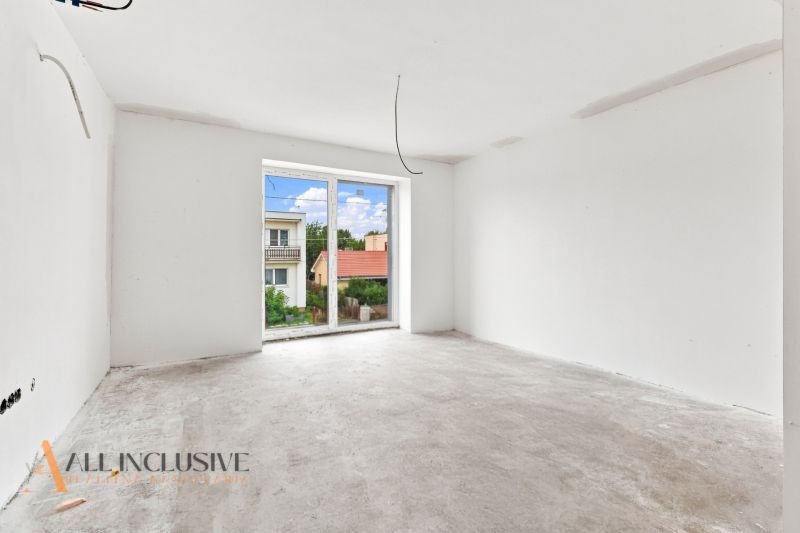 Ein Zimmer in einem Einfamilienhaus mit einem unbefestigten Boden, einem großen Fenster und Blick auf die Gärten.