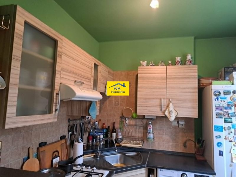 Küche in einer 2-Zimmer-Wohnung mit Holzschränken und grüner Wand.