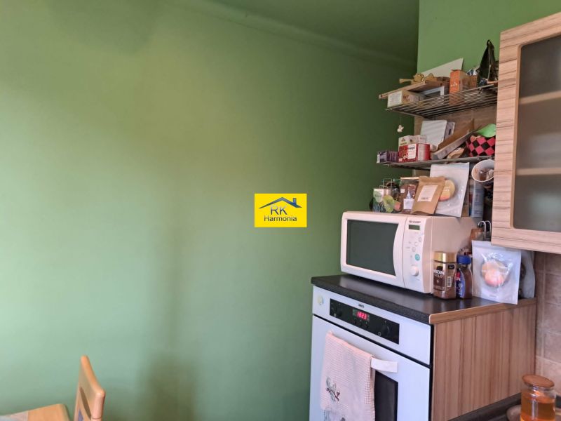 Küche in einer 2-Zimmer-Wohnung mit Mikrowelle und offenen Regalen.