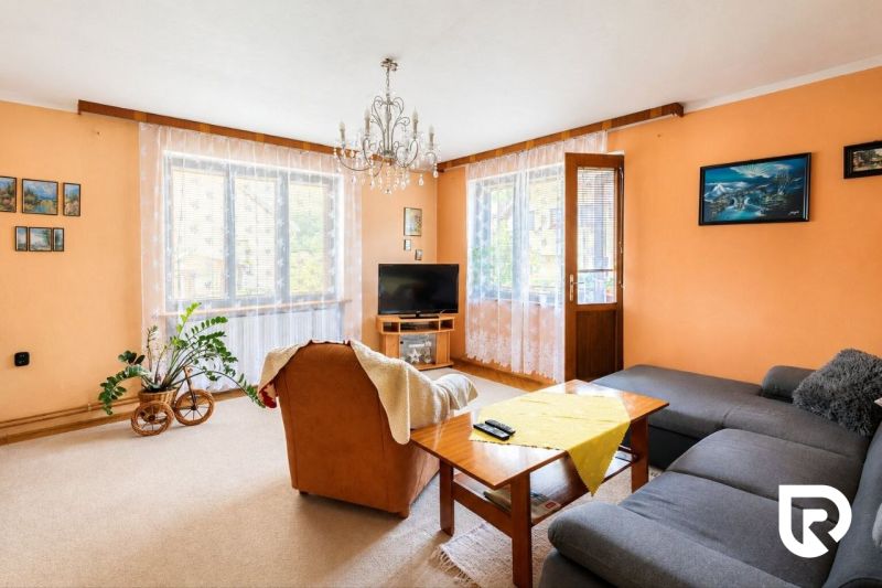 Wohnzimmer mit cremefarbenen Wänden, einem orangefarbenen Sessel und einem grauen Sofa in einem Einfamilienhaus.