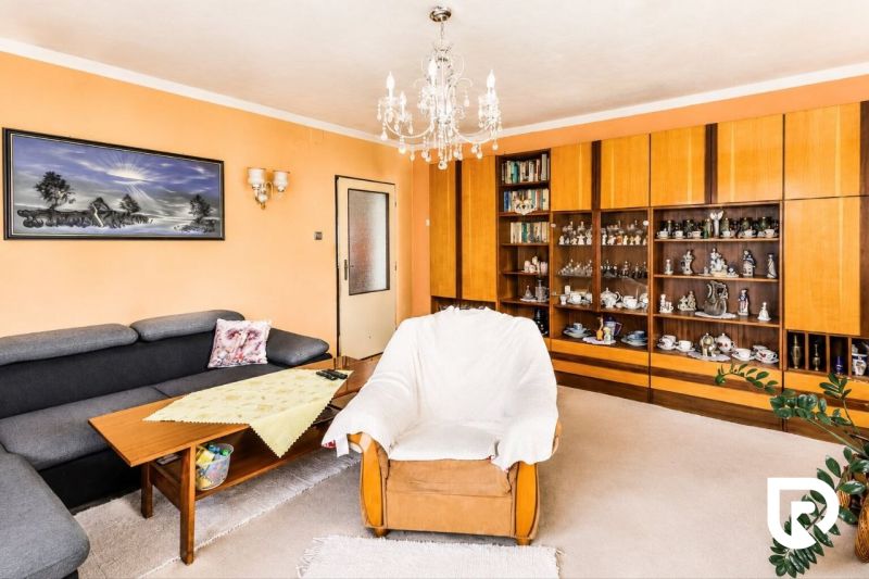Wohnzimmer in einem Einfamilienhaus mit Sessel, Sofa und einer Vitrine voller Keramik.
