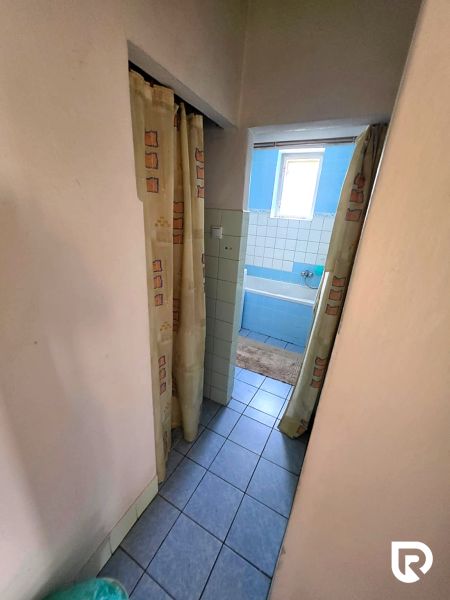 Badezimmer im Einfamilienhaus mit blauer Badewanne und Vorhängen, Fliesen auf dem Boden.