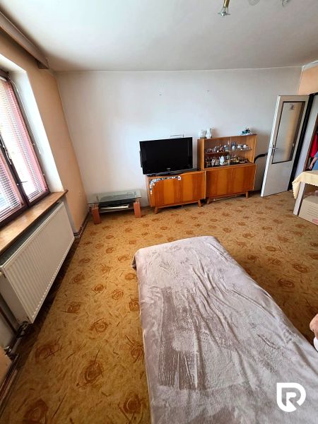 Wohnzimmer in einem Einfamilienhaus mit Fernseher, Vitrinen und dekorativem Teppich.