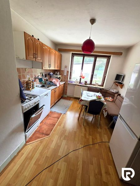 Küche mit Holzelementen, Gasherd, Kühlschrank und Esstisch in einem Einfamilienhaus.