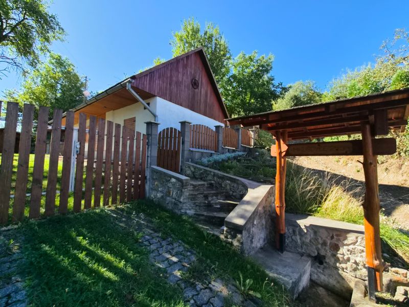 Ein Einfamilienhaus in Mikušovce mit einem Holzzaun und einer Steintreppe.