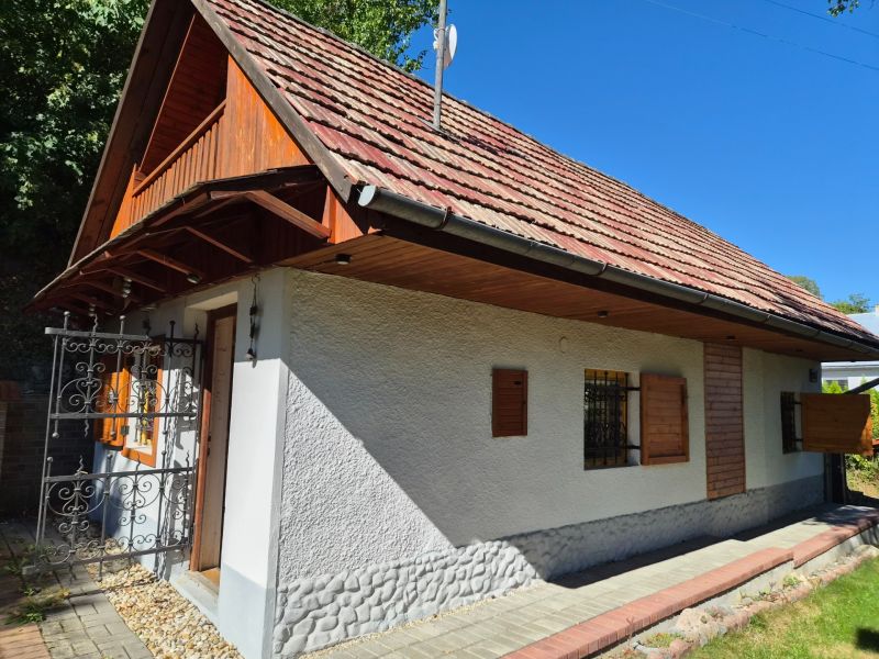 Ein Einfamilienhaus in Mikušovce mit Holzläden und einem roten Dach, umgeben von Grün.