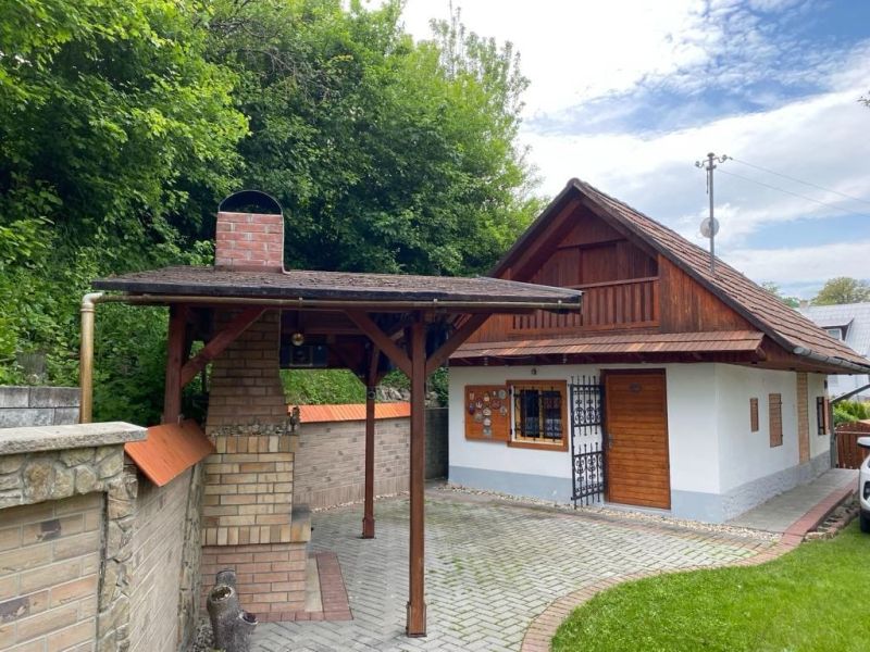Ein Einfamilienhaus in Mikušovce mit einem Gartenunterstand und einem Ziegelkamin.