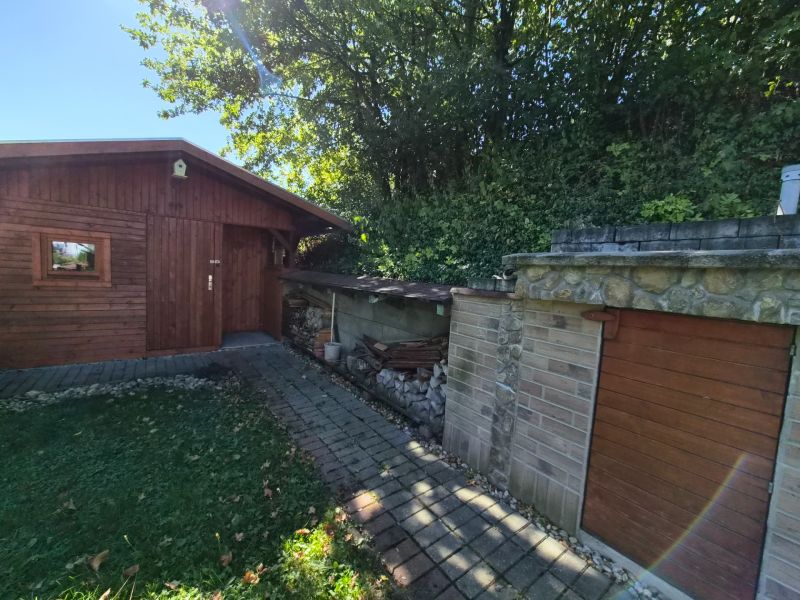 Ein Holzunterstand und ein Steingebäude im Garten eines Einfamilienhauses in Mikušovce.
