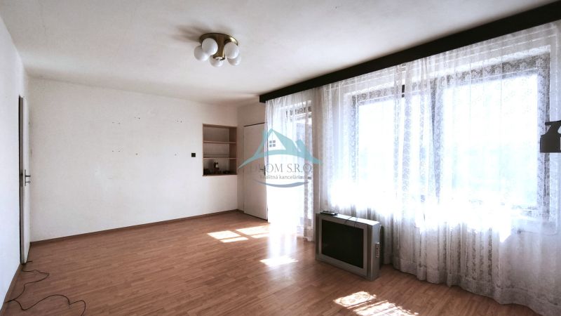 Wohnzimmer in einem Einfamilienhaus mit Holzboden und großen Fenstern mit Vorhängen.