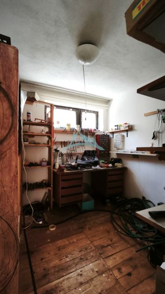 Werkstatt mit Regalen und Holztisch in einem Einfamilienhaus, Boden mit Holzdekor.
