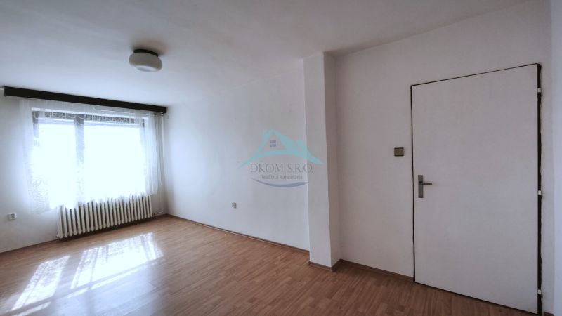 Ein geräumiges Zimmer in einem Einfamilienhaus mit einem Holzboden und einem großen Fenster.