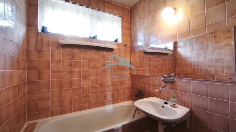 Badezimmer eines Einfamilienhauses mit Badewanne, Waschbecken und gefliesten Wänden in einem braunen Farbton.