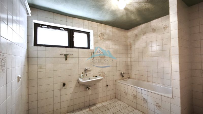 Badezimmer mit Fliesen, Waschbecken und Badewanne in einem Einfamilienhaus.