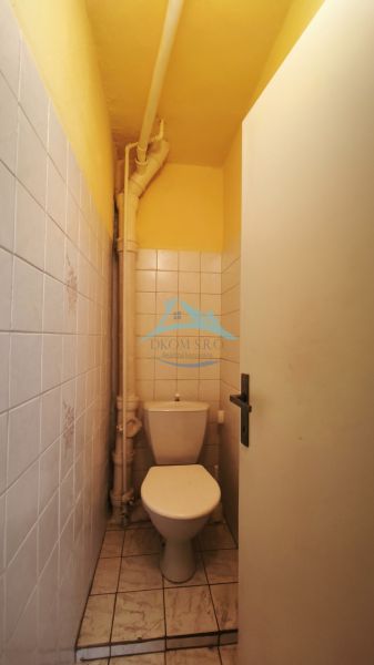 Ein kleines, schmales WC mit Fliesen in einem Einfamilienhaus mit weißen Kacheln.