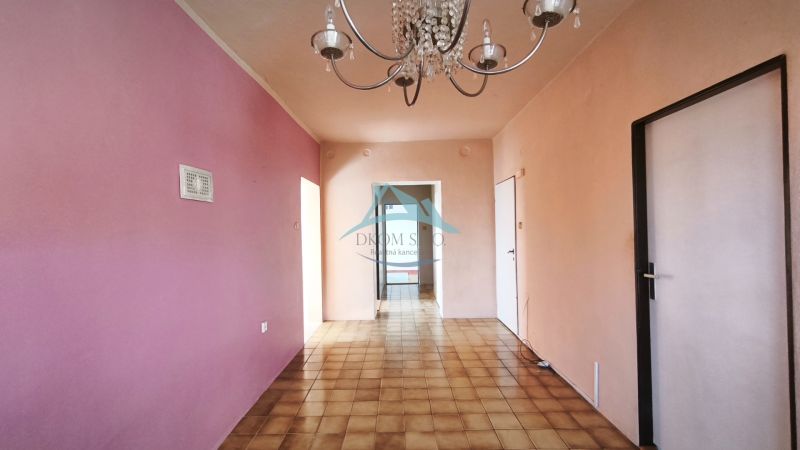 Innenraum eines Einfamilienhauses mit Kronleuchter, rosa Wand und Fliesenboden.