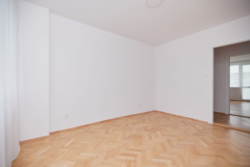 Ein Raum mit hellen Wänden und einem Boden in Holzoptik in einer 3-Zimmer-Wohnung.