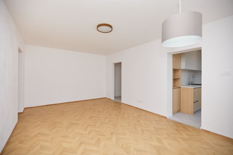 Wohnzimmer in einer 3-Zimmer-Wohnung mit Holzboden und Zugang zur Küche.