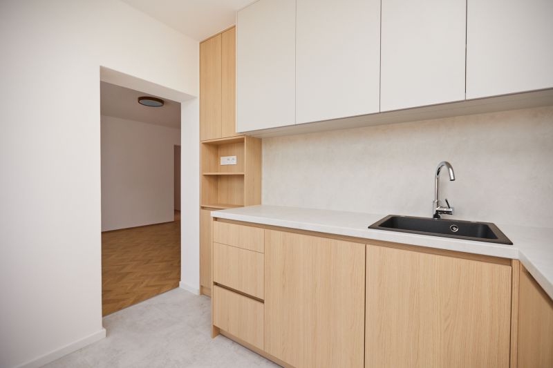 Eine Küchenzeile mit hellen Schränken und einem Boden in Holzoptik, 3-Zimmer-Wohnung.