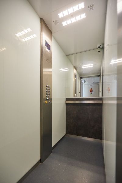 Innenraum eines Aufzugs mit Knöpfen, Edelstahlelementen und Spiegeln in einer 3-Zimmer-Wohnung.