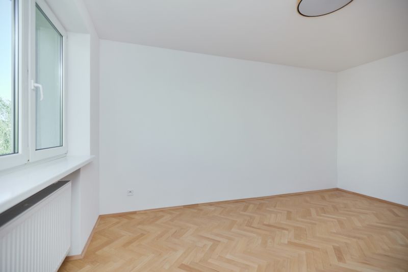 Ein leerer Raum mit Holzboden in einer 3-Zimmer-Wohnung.