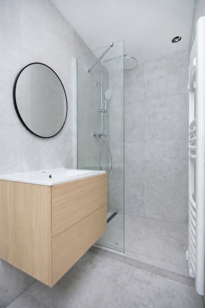 Badezimmer in einer 3-Zimmer-Wohnung mit moderner Duschkabine und Holzdekor auf dem Schrank.