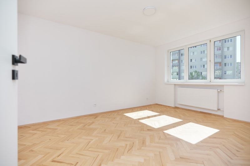 Ein heller Raum mit weißen Wänden und einem Boden in Holzoptik in einer 3-Zimmer-Wohnung.