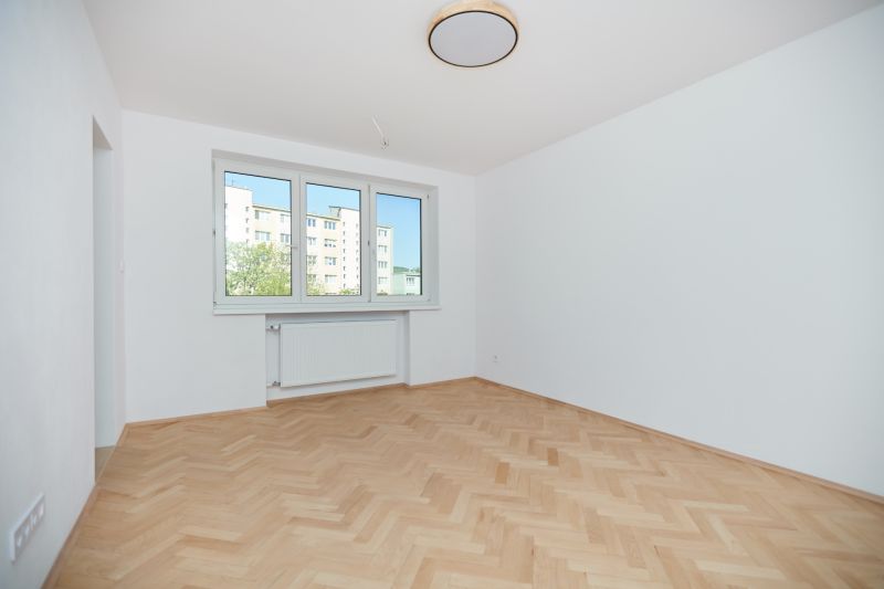 Ein Zimmer in einer 3-Zimmer-Wohnung mit weißen Wänden und einem Boden in Holzoptik.
