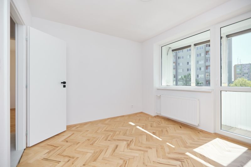 Ein Zimmer in einer 3-Zimmer-Wohnung mit einem Boden in Holzoptik und einem großen Fenster.