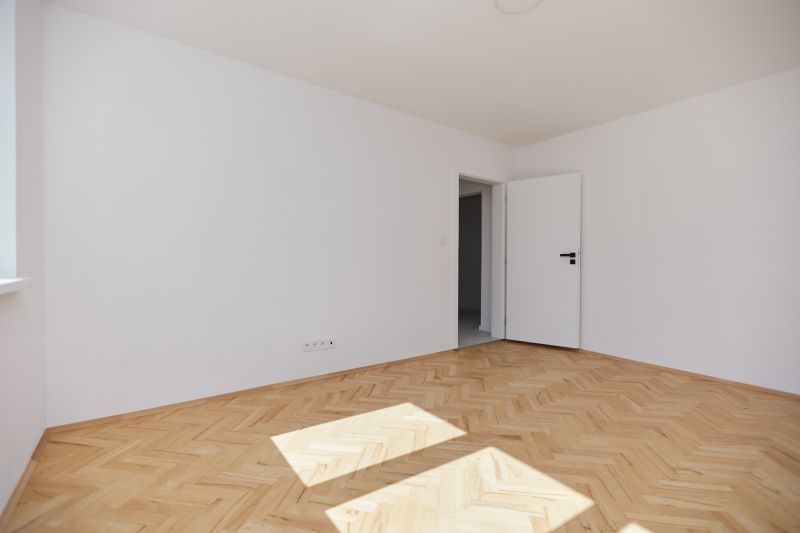 Helles Zimmer mit weißen Wänden und einem Boden in Holzoptik, 3-Zimmer-Wohnung.