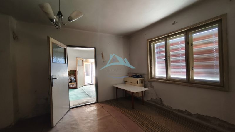 Ein Innenraum in einem Einfamilienhaus mit offenen Türen und einem Tisch am Fenster.