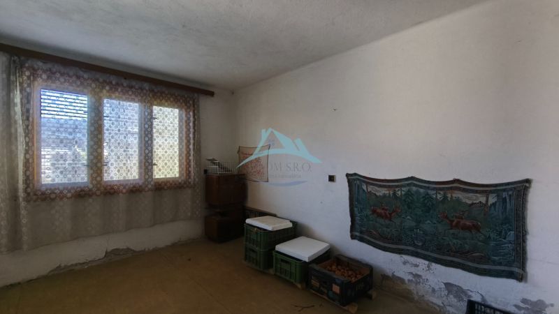 Ein Zimmer in einem Einfamilienhaus mit einem großen Fenster, einem Vorhang und minimalistischer Einrichtung.