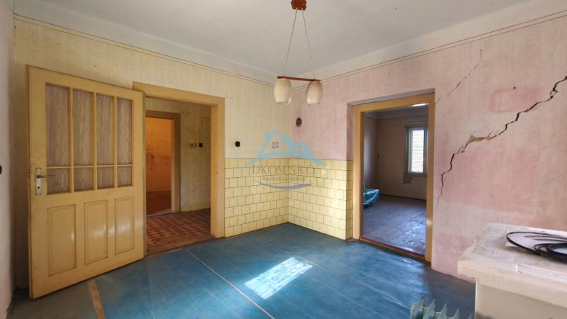 Ein Zimmer mit einem blauen Boden mit Holzdekor, alten Türen und Rissen in der Wand.