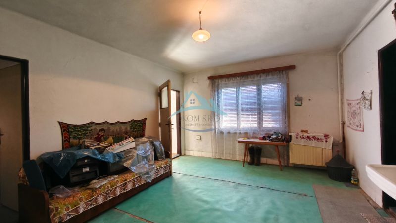 Ein Zimmer in einem Einfamilienhaus mit Teppichboden, einem Sofa und einem Fenster mit Vorhang.