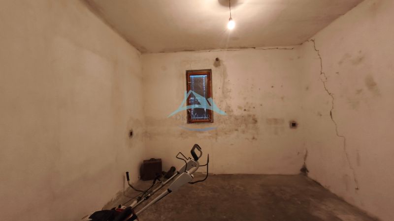 Keller mit Fenster in einem Einfamilienhaus, Wände mit Rissen und einfacher Beleuchtung.