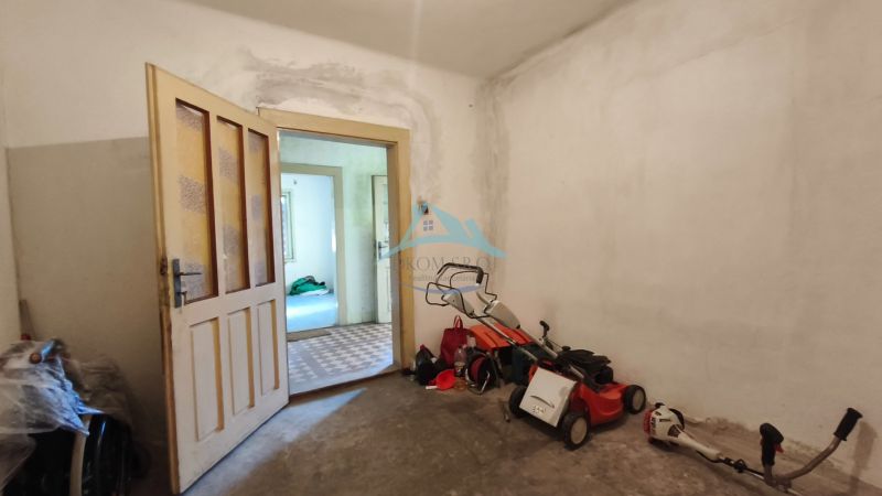 Das Innere eines Einfamilienhauses mit offenen Türen, einem Rasenmäher und Werkzeugen auf dem Boden.